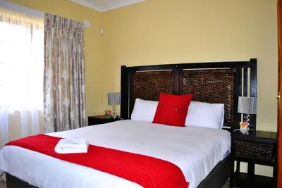 a bedroom with a large bed with red pillows at Mount Azimbo Lodge in Louis Trichardt