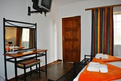 a room with two beds and a desk and a mirror at Mount Azimbo Lodge in Louis Trichardt
