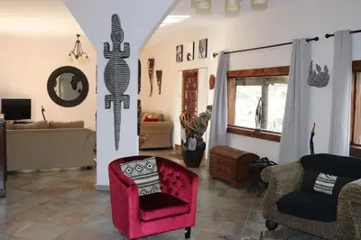 a living room with a red chair and a couch at Hakuna Matata in Marloth Park