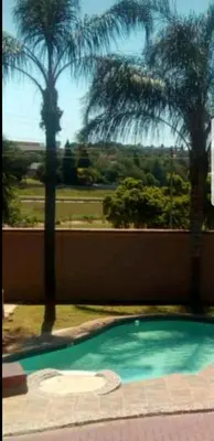 a swimming pool with palm trees in the background at LANGA 'S COZY GUESTHOUSE in Pretoria