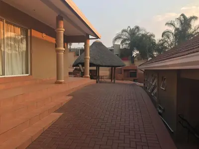 a brick walkway next to a house with columns at LANGA 'S COZY GUESTHOUSE in Pretoria