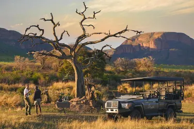 a jeep parked in a field with people standing next to it at Marataba Mountain Lodge in Kransberg