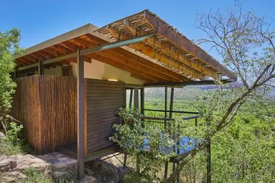 a small house with a wooden roof and a chair at Marataba Mountain Lodge in Kransberg