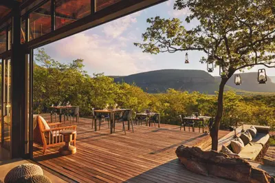 a wooden deck with tables and chairs and a tree at Marataba Mountain Lodge in Kransberg