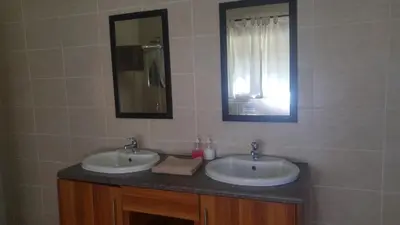 a bathroom with two sinks and a mirror at Roaring Sky Base Camp in Baviaanspoort
