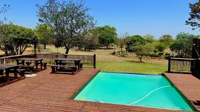 a deck with a picnic table and a swimming pool at Roaring Sky Base Camp in Baviaanspoort