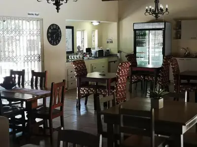 a restaurant with tables and chairs and a kitchen at Stay@Sparks Guesthouse in Lephalale