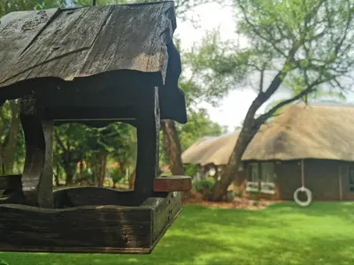 a wooden structure in the grass with a hut in the background at Stay@Sparks Guesthouse in Lephalale
