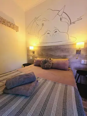 a bedroom with a bed with a picture of a pig on the wall at Kruger Dreams Lodge in Marloth Park