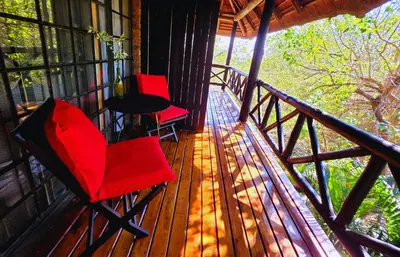 two red chairs and a table on a porch at Kruger Dreams Lodge in Marloth Park