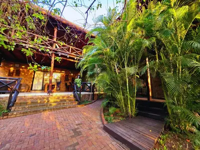a building with a brick walkway and palm trees in front at Kruger Dreams Lodge in Marloth Park