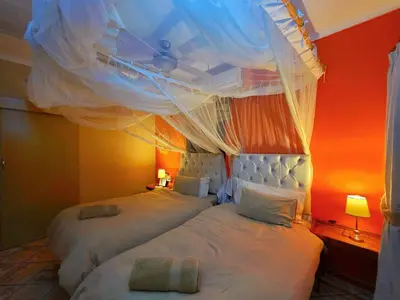 two beds in a bedroom with an orange wall at Kruger Dreams Lodge in Marloth Park