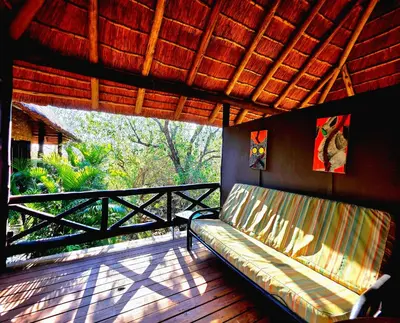 a couch sitting on a porch with a balcony at Kruger Dreams Lodge in Marloth Park