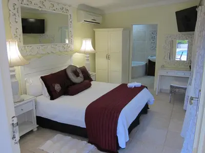 a bedroom with a bed and a bathroom with a tub at La Barune Guest House in Tzaneen