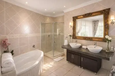 a bathroom with two sinks and a tub and a mirror at La Barune Guest House in Tzaneen
