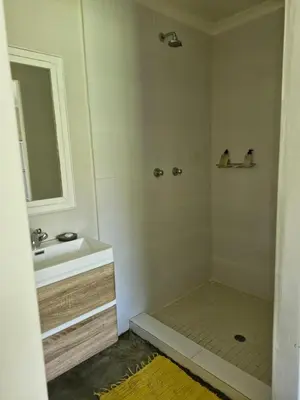 a bathroom with a sink and a shower with a mirror at Blue Hills Lodge in Midrand