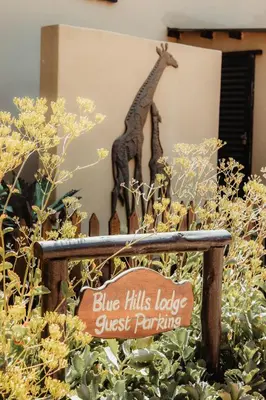 a blue hills lodge guest parking sign with a giraffe statue at Blue Hills Lodge in Midrand