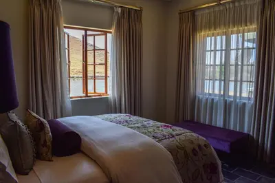 a bedroom with a bed and a window at Ambassador Lodge in Dullstroom