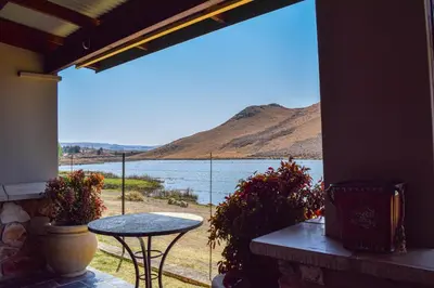 a patio with a table and a view of a lake at Ambassador Lodge in Dullstroom