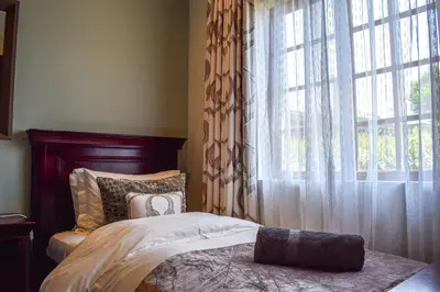 a bedroom with a bed and a large window at Ambassador Lodge in Dullstroom