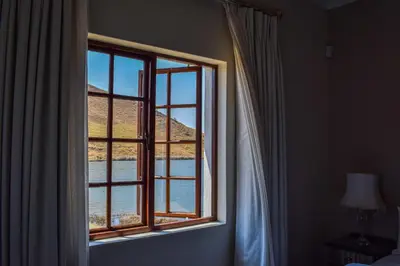 a window in a bedroom looking out at the water at Ambassador Lodge in Dullstroom