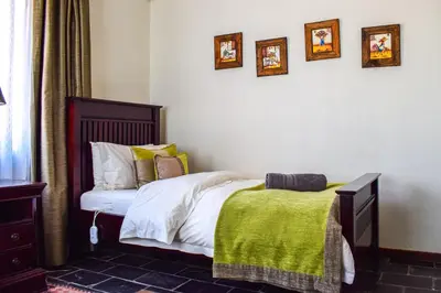 a bedroom with a bed with a green blanket at Ambassador Lodge in Dullstroom