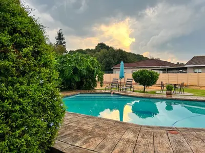 a swimming pool with a table and chairs in a yard at Aerodrome Lodge and Conference Centre in Benoni