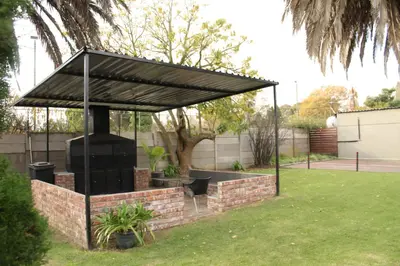 a barbecue grill with a black canopy in a yard at Livingwaters Self-Catering Accommodation in Ermelo