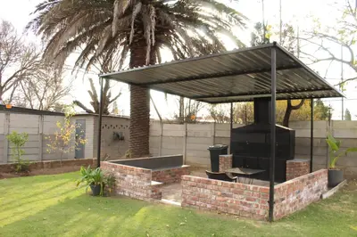a barbecue grill with a roof in a yard at Livingwaters Self-Catering Accommodation in Ermelo