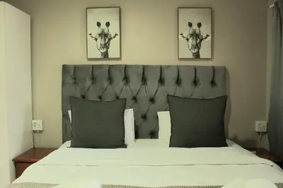 a bedroom with a large bed with two pictures on the wall at Livingwaters Self-Catering Accommodation in Ermelo