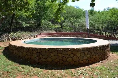 a stone wall around a swimming pool in a yard at KweKwe Private Game Lodge in Marble Hall