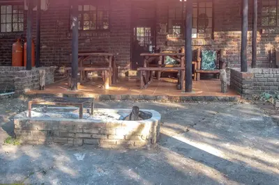 a patio with tables and benches in a brick building at Owl House Marloth Park in Marloth Park