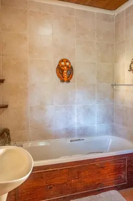 a bathroom with a bath tub and a sink at Owl House Marloth Park in Marloth Park