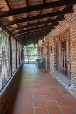 an empty porch with a brick wall and a wooden ceiling at Owl House Marloth Park in Marloth Park
