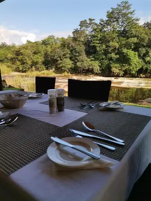 a table with plates and utensils on top of it at Lions Rock Rapids - Luxury Tented Camp in Hazyview