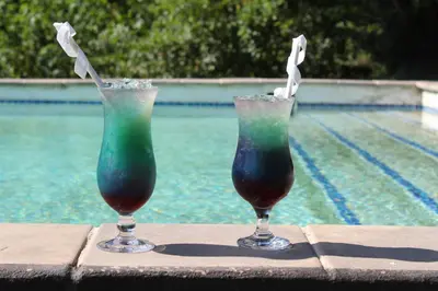 two drinks sitting on a table next to a pool at Lions Rock Rapids - Luxury Tented Camp in Hazyview