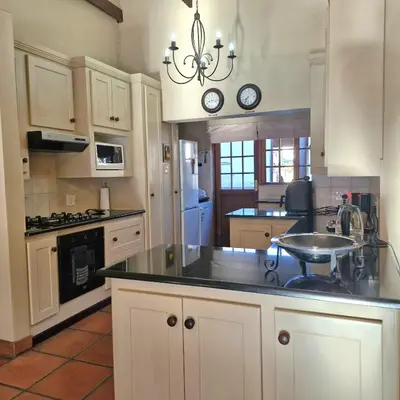 a kitchen with white cabinets and a black counter top at Aviemore Lodge in Dullstroom
