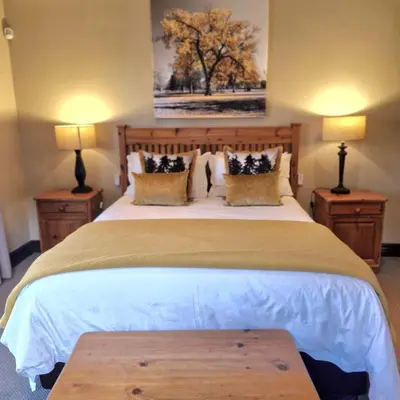 a bedroom with a large bed with two lamps at Aviemore Lodge in Dullstroom