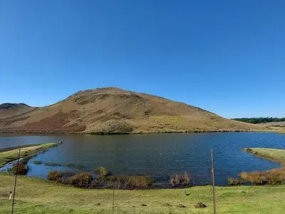 a large body of water with a hill in the background at Aviemore Lodge in Dullstroom