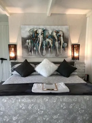 a bedroom with a bed with a painting of elephants at White River B & B in White River