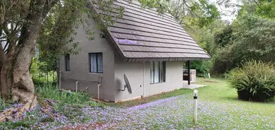 a small house with a shingled roof in a yard at Wild Forest Inn in Graskop