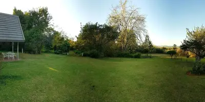 a large yard with trees and a house at Wild Forest Inn in Graskop