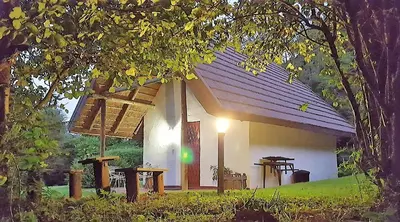 a small white house with a light on the front at Wild Forest Inn in Graskop