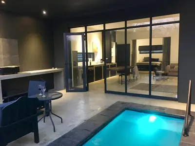 a living room with a swimming pool and a kitchen at Ochre House in Marloth Park