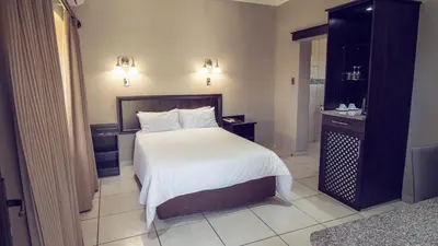 a bedroom with a large bed with white sheets at Machauka Lodge in Lephalale