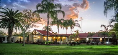 a house with palm trees in front of it at Machauka Lodge in Lephalale