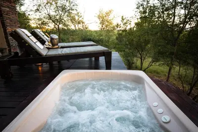 a jacuzzi tub on a patio with two chairs at Parsons Hilltop Safari Camp in Balule Game Reserve