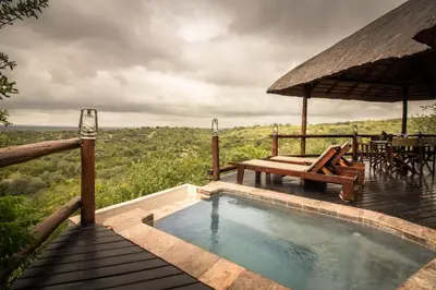 a swimming pool on a deck with a table and chairs at Parsons Hilltop Safari Camp in Balule Game Reserve