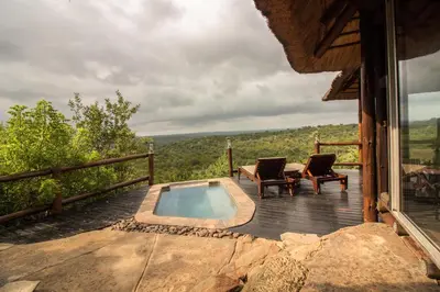 a pool on a deck with two chairs and a table at Parsons Hilltop Safari Camp in Balule Game Reserve