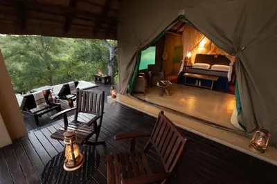 a room with a bed and chairs in a tent at Parsons Hilltop Safari Camp in Balule Game Reserve